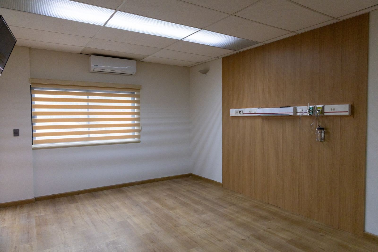 Habitación con persiana zebra, muro de lambrín y panel de servicios