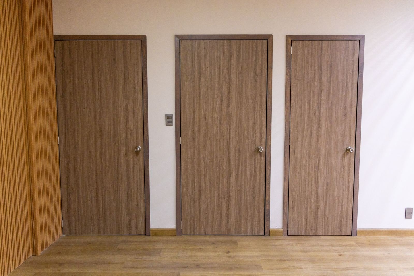 Puertas de madera con marco a juego y muro de lambrín ranurado