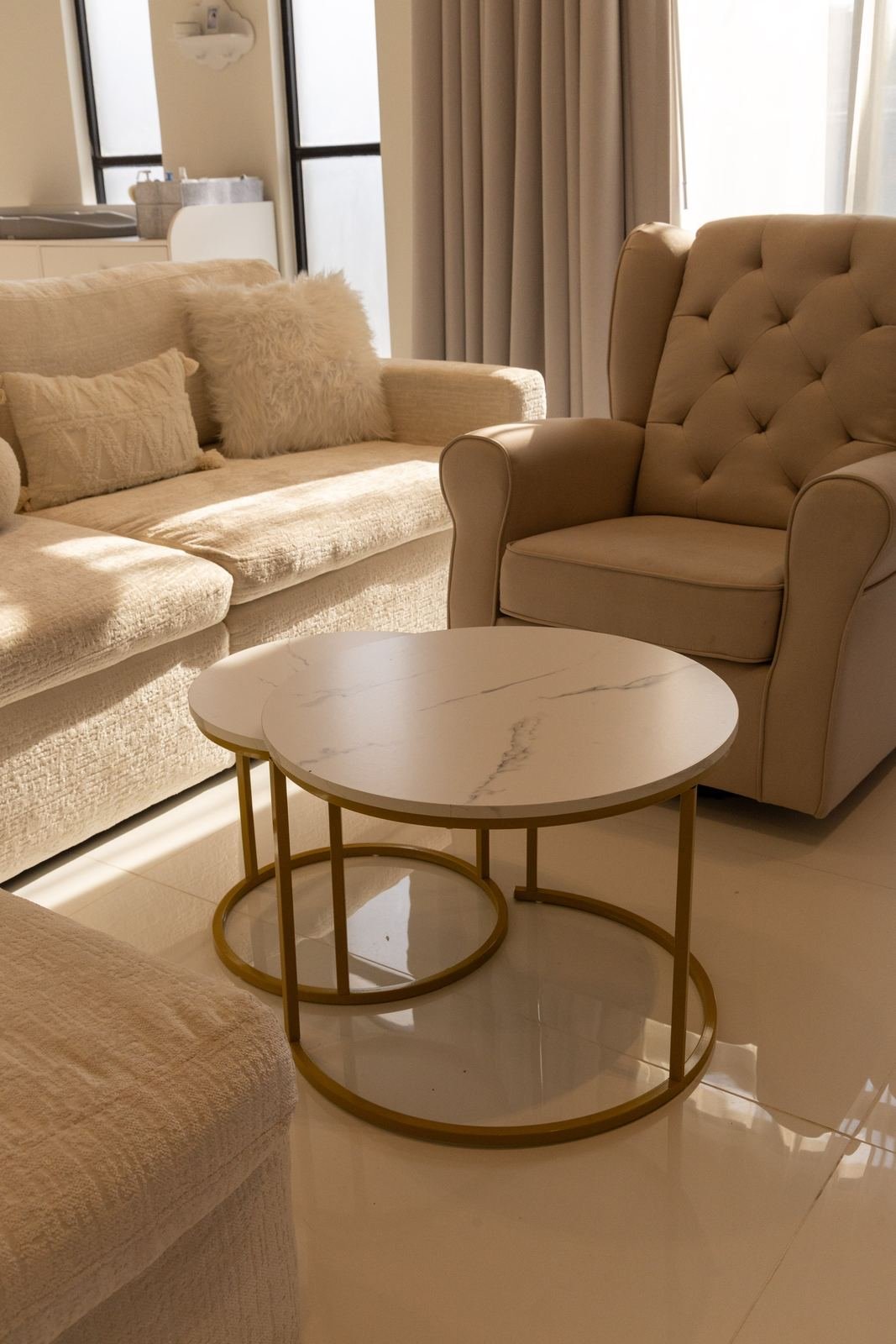 Sala de estar con mesas de mármol, sofá y sillón capitonado