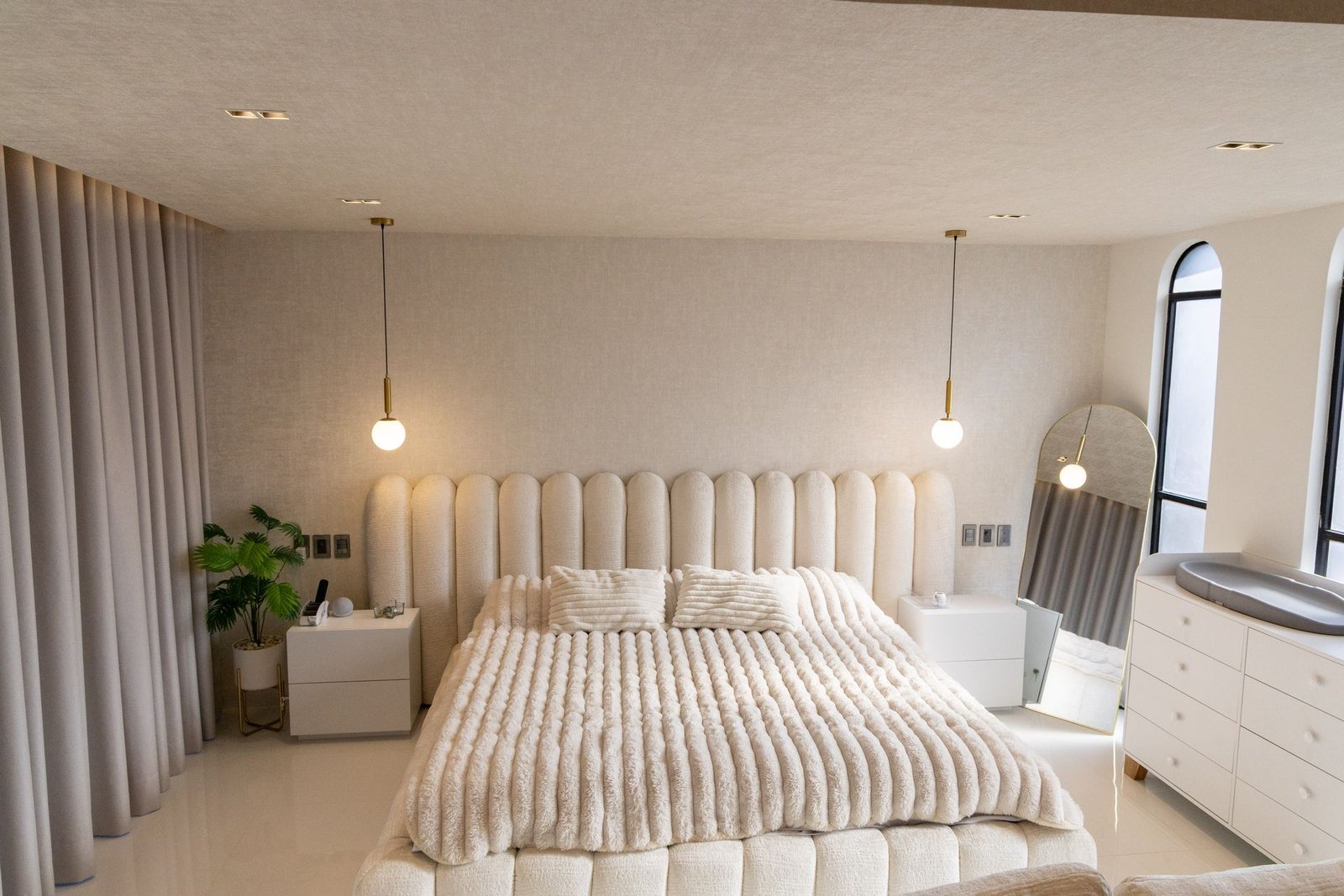 Recámara real con cabecera a medida, lámparas colgantes y luz cálida, proyecto Decora