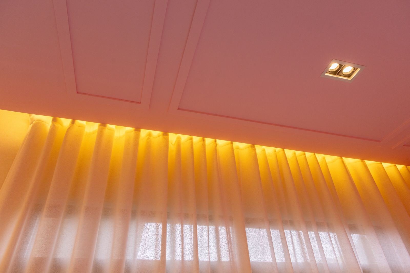 Tocador con cubierta de cristal, sillón afelpado, cortinas y plafón rosa con luz indirecta