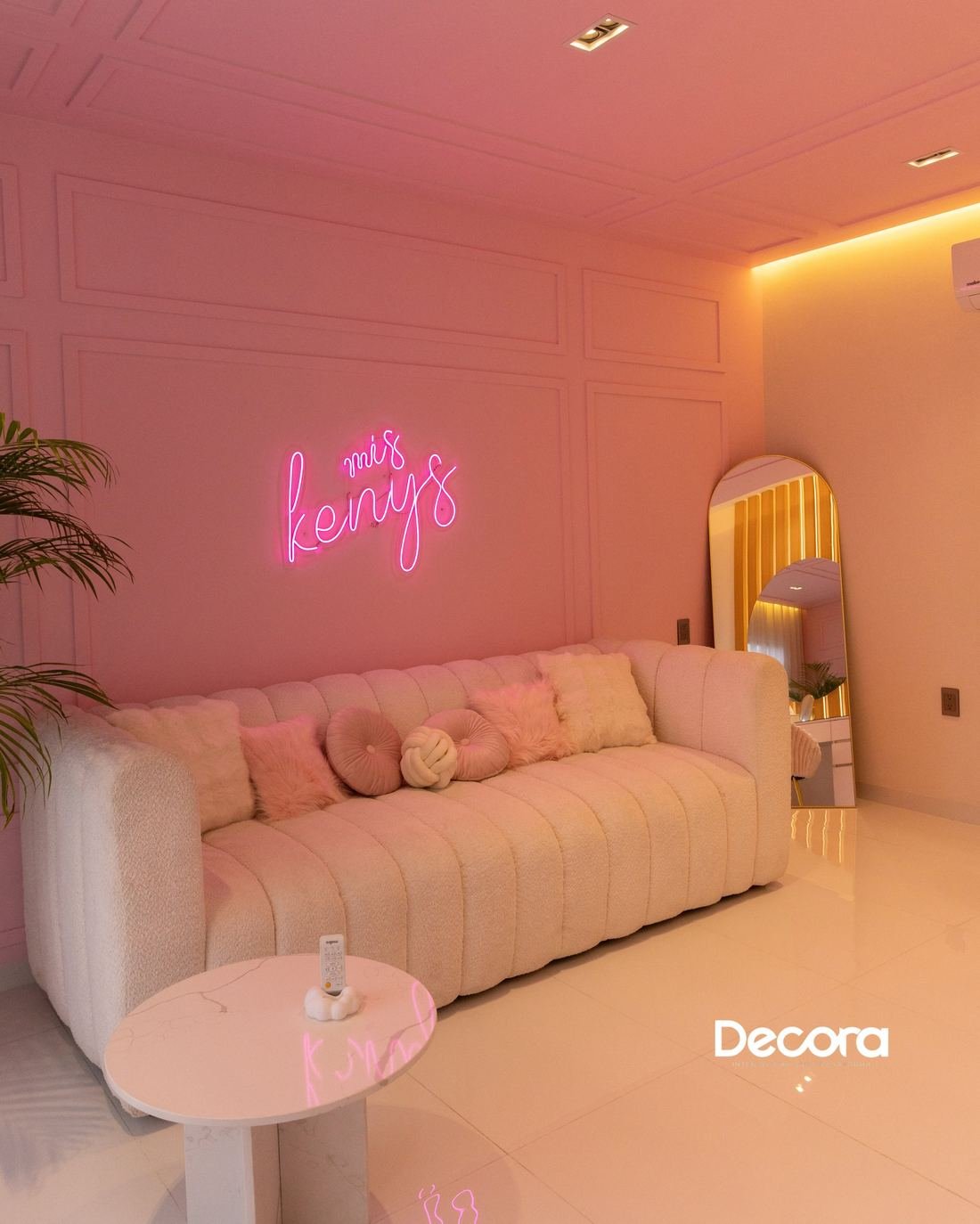 Sala rosa con neón, sofá capitoné y espejo de arco