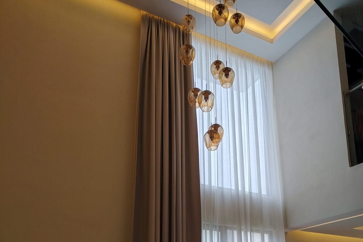 Cortinas de doble altura, blackout y visillo, con iluminación integrada en proyecto de Decora